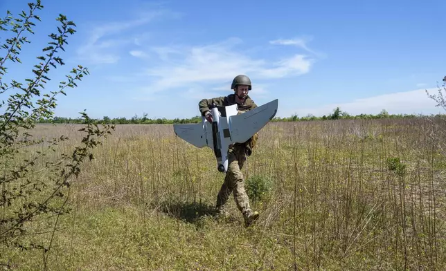 A Ukrainian serviceman Dmytro of 148th separate artillery brigade of the Air Assault Forces carries a Furia drone after landing by a parachute at the frontline in Donetsk region, Ukraine, Thursday May 9, 2024. (AP Photo/Evgeniy Maloletka)