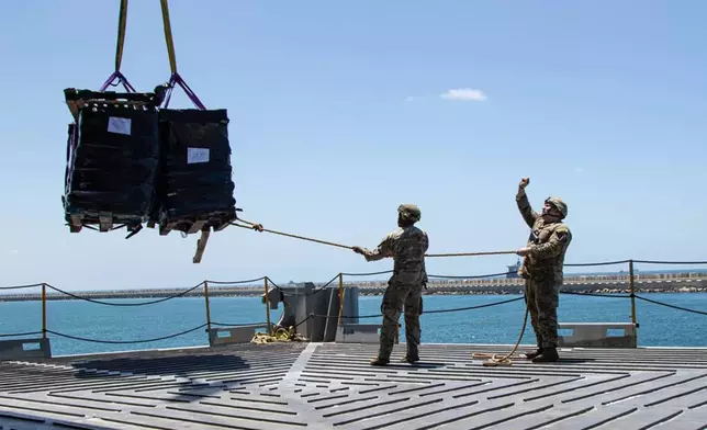 U.S. Army soldiers assigned to the 7th Transportation Brigade (Expeditionary) use a rope to stabilize humanitarian aid while it is lifted by a crane aboard the MV Roy P. Benavidez to support the Joint Logistics Over-the-shore (JLOTS) operation, in the Port of Ashdod, Israel, May 13, 2024. (Staff Sgt. Malcolm Cohens-Ashley/U.S. Army via AP)