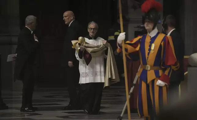 A deacon brings the papal robe for Pope Francis who will preside over the second vespers in St. Peter's Basilica on Ascension Day, Thursday, May 9, 2024, after reading the papal bull 'Spes non confundit' (Latin for, hope does not disappoint), the official decree establishing the Catholic Holy Year: a once-every-quarter-century event that is expected to bring some 32 million pilgrims to Rome (AP Photo/Gregorio Borgia)