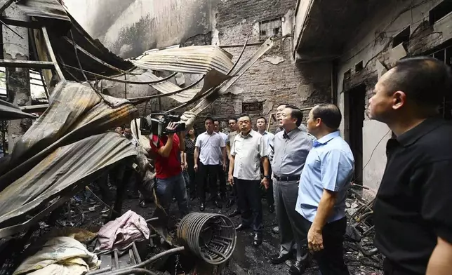 Officials visit the site of a house fire in Hanoi, Vietnam Friday, May 24, 2024. Authorities said the fire has killed a number of people and injured a few others. (Bui Van Lanh/VNA via AP)