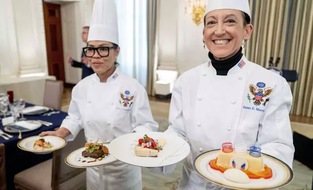 FILE - White House executive chef Cris Comerford, left, and White House executive pastry chef Susie Morrison, right, hold dishes during a media preview for the State Dinner with President Joe Biden and French President Emmanuel Macron in the State Dining Room of the White House in Washington, Nov. 30, 2022. (AP Photo/Andrew Harnik, File)