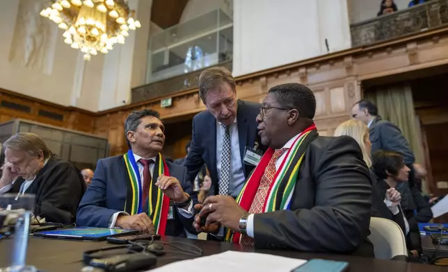 South Africa's agents Vusimuzi Madonsela, seated right, and Cornelius Scholtz, seated second left, talk prior to the start of hearings at the International Court of Justice, in The Hague, Netherlands, Thursday, May 16, 2024. The U.N.'s top court opened two days of hearings in a case brought by South Africa to see whether Israel needs to take additional measures to alleviate the suffering in war-ravaged Gaza. (AP Photo/Peter Dejong)