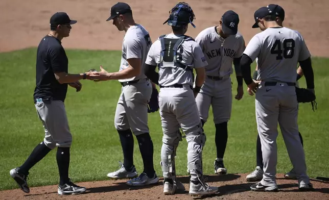 New York Yankees manager Aaron Boone, left, pulls starting pitcher Carlos Rodon, second from left, during the fifth inning of a baseball game against the Baltimore Orioles, Thursday, May 2, 2024, in Baltimore. (AP Photo/Nick Wass)