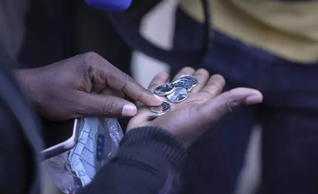 A woman shows the new Zimbabwean bank coins called the ZiG, in the streets of Harare, Zimbabwe, Tuesday, April 30, 2024. Zimbabwe started circulating banknotes and coins for another new currency Tuesday in its latest attempt to solve a long-running and at times baffling monetary crisis that has seen the government try gold coins and a digital currency among other ideas. (AP Photo/Tsvangirayi Mukwazhi)