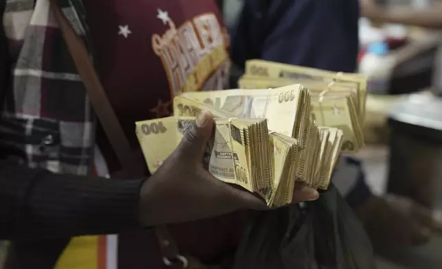 A woman uses old Zimbabwean dollar notes to buy groceries in a supermarket in Harare, Thursday, April 25, 2024. Zimbabwe started circulating banknotes and coins for another new currency Tuesday in its latest attempt to solve a long-running monetary crisis that has seen the government try gold coins and a digital currency among other ideas. (AP Photo/Tsvangirayi Mukwazhi)