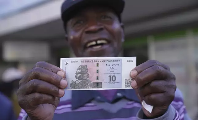 A man smiles while holding the new Zimbabwean banknote, called the ZiG, in the streets of Harare, Zimbabwe, Tuesday, April 30, 2024. Zimbabwe started circulating banknotes and coins for another new currency Tuesday in its latest attempt to solve a long-running and at times baffling monetary crisis that has seen the government try gold coins and a digital currency among other ideas. (AP Photo/Tsvangirayi Mukwazhi)