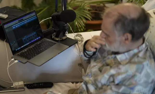 Michael Bommer, who is terminally ill with colon cancer, listens to his AI generated voice during a meeting with The Associated Press at his home in Berlin, Germany, Wednesday, May 22, 2024. Bommer, who has only a few more weeks to live, teamed up with friend who runs the AI-powered legacy platform Eternos to "create a comprehensive, interactive AI version of himself, allowing relatives to engage with his life experiences and insights," after he has passed away. (AP Photo/Markus Schreiber)