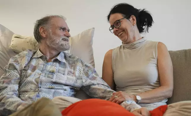 Michael Bommer, left, who is terminally ill with colon cancer, looks at his wife Anett Bommer during a meeting with The Associated Press at his home in Berlin, Germany, Wednesday, May 22, 2024. Bommer, who has only a few more weeks to live, teamed up with friend who runs the AI-powered legacy platform Eternos to "create a comprehensive, interactive AI version of himself, allowing relatives to engage with his life experiences and insights," after he has passed away. (AP Photo/Markus Schreiber)