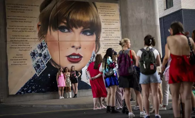 Taylor Swift fans pose for a photograph besides a mural, commissioned by London Mayor Sadiq Khan, before the first London concert of the Eras Tour on Friday, June 21, 2024 in London. (Photo by Scott A Garfitt/Invision/AP)