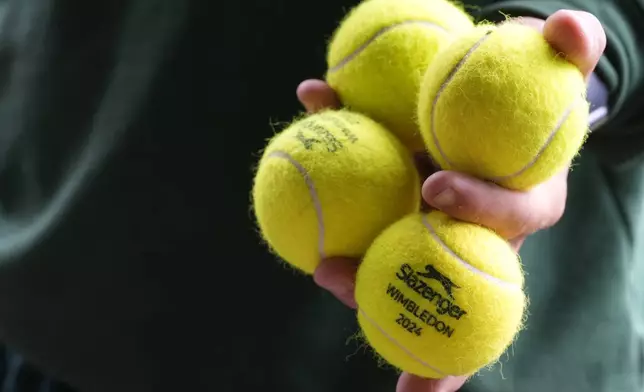 A groundsman carries tennis balls at the All England Lawn Tennis and Croquet Club in Wimbledon, London, Friday, June 28, 2024. The Wimbledon Championships begin on July 1. (AP Photo/Kirsty Wigglesworth)