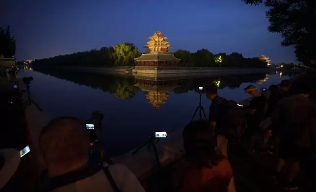 Local residents take cellphone photos of the the Turret of the Forbidden City during dusk, Friday, June 28, 2024, in Beijing, China, (AP Photo/Vincent Thian)