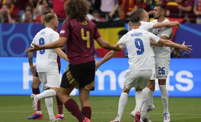 Slovakia's Ivan Schranz, right, is hugged by teammates after scoring during a Group E match between Belgium and Slovakia at the Euro 2024 soccer tournament in Frankfurt, Germany, Monday, June 17, 2024. (AP Photo/Darko Vojinovic)