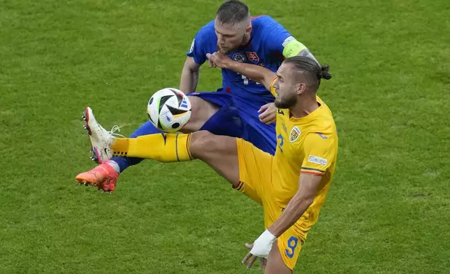 Romania's George Puscas, right, and Slovakia's Milan Skriniar struggle for the ball during a Group E match at the Euro 2024 soccer tournament in Frankfurt, Germany, Wednesday, June 26, 2024. (AP Photo/Darko Vojinovic)