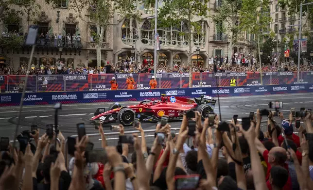 Ferrari's Carlos Sainz of Spain drives during the Formula 1 Barcelona Fan Festival along the Passeig de Gracia in downtown Barcelona, Spain, Wednesday, June 19, 2024. (AP Photo/Emilio Morenatti)