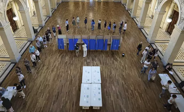 Voters wait at a polling station to vote in the first round of the French parliamentary election, in Lyon, central France, Sunday, June 30, 2024. Voters across mainland France are casting ballots in the first round of an exceptional parliamentary election. (AP Photo/Laurent Cipriani)