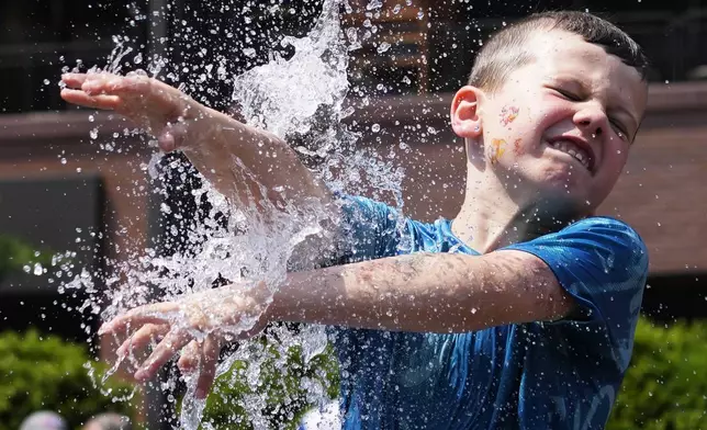 A boy cools off at a fountain outside Wrigley Field before a baseball game between the Chicago Cubs and St. Louis Cardinals as hot weather descends upon the Chicago area Sunday, June 16, 2024. (AP Photo/Nam Y. Huh