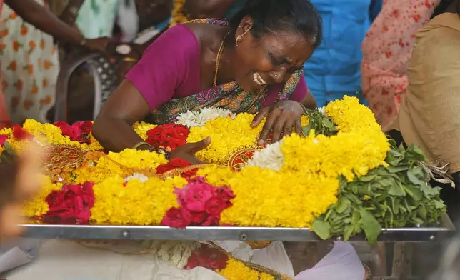 A relative of a man, who died after drinking illegally brewed liquor, cries over a casket containing his body, in Kallakurichi district of the southern Indian state of Tamil Nadu, India, Thursday, June 20, 2024. The state's chief minister M K Stalin said the 34 died after consuming liquor that was tainted with methanol, according to the Press Trust of India news agency. (AP Photo/R. Parthibhan)