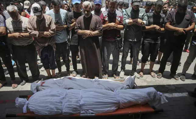 Mourners pray for two Palestinians during their funeral at Al-Aqsa Martyrs Hospital in Deir al Balah, Gaza Strip, Friday, June 14, 2024. An Israeli airstrike on a home in the central city in the Gaza Strip killed two people and wounded several others including children, hospital officials said. (AP Photo/Mohammad Hajjar)