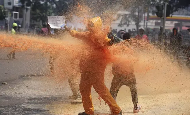 Protesters scatter as Kenya police spray a water canon at them during a protest over proposed tax hikes in a finance bill in downtown Nairobi, Kenya Tuesday, June 25, 2024. (AP Photo/Brian Inganga)