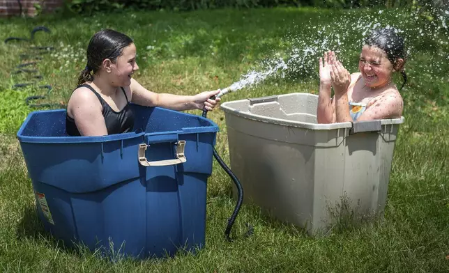 Best friends Anna Labelle, left and Frankie Russell got creative Tuesday morning, June 18, 2024, to help stay cool in Labelle's backyard in Auburn, Maine, as the temperature began to climb. (Russ Dillingham/Sun Journal via AP)