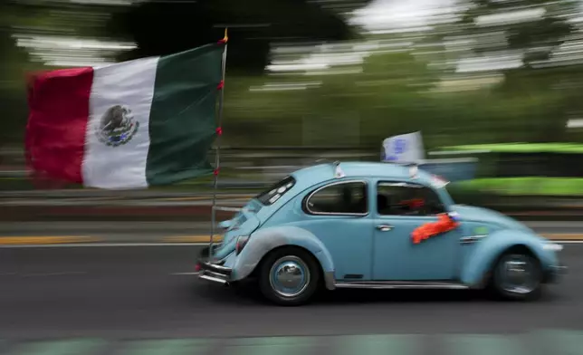 An antique Volkswagen Beetle, known in Mexico as a "vocho," parades through the streets a day after World Vocho Day, in Mexico City, Sunday, June 23, 2024. (AP Photo/Marco Ugarte)