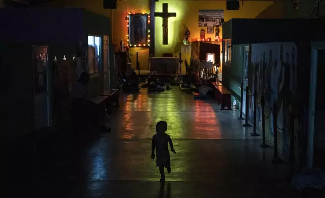 A young migrant runs through the Peace Oasis of the Holy Spirit Amparito shelter where migrants sleep on the floor on mats in Villahermosa, Mexico, late Friday, June 7, 2024. After the head of Mexico's immigration agency ordered a halt to deportations in December, migrants have been left in limbo as authorities round up migrants across the country and dump them in the southern Mexican cities of Villahermosa and Tapachula. (AP Photo/Felix Marquez)