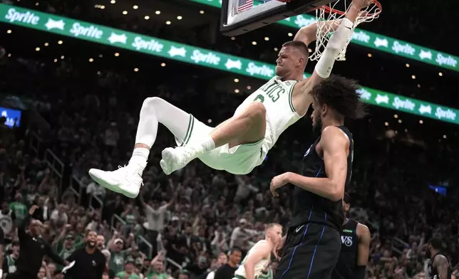 Boston Celtics center Kristaps Porzingis dunks next to Dallas Mavericks center Dereck Lively II, foreground, during the first half of Game 1 of basketball's NBA Finals on Thursday, June 6, 2024, in Boston. (AP Photo/Charles Krupa)