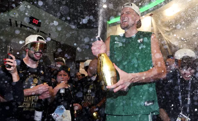 Boston Celtics center Kristaps Porzingis sprays champagne while celebrating after defeating the Dallas Mavericks in Game 5 to win the NBA basketball finals Monday, June 17, 2024, in Boston. (Elsa/Pool Photo via AP)
