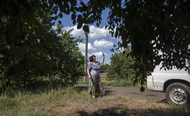 A local woman tries to find a signal for her phone before she leaves her home during evacuation to safe areas, in Toretsk, Donetsk region, Ukraine, Friday, June 28, 2024. (AP Photo/Evgeniy Maloletka)