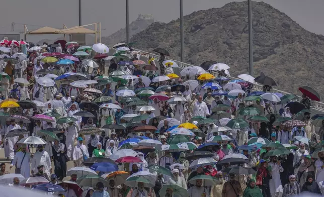 Muslim pilgrims use umbrellas to shield themselves from the sun as they arrive to cast stones at pillars in the symbolic stoning of the devil, the last rite of the annual hajj, in Mina, near the holy city of Mecca, Saudi Arabia, Tuesday, June 18, 2024. Muslim pilgrims were wrapping up the Hajj pilgrimage in the deadly summer heat on Tuesday with the third day of the symbolic stoning of the devil, and the farewell circling around Kaaba in Mecca's Grand Mosque. (AP Photo/Rafiq Maqbool)