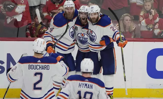 Edmonton Oilers players congratulate center Connor McDavid (97) after McDavid scored a goal during the third period of Game 5 of the NHL hockey Stanley Cup Finals against the Florida Panthers, Tuesday, June 18, 2024, in Sunrise, Fla. The Oilers defeated the Panthers 5-3. (AP Photo/Rebecca Blackwell)