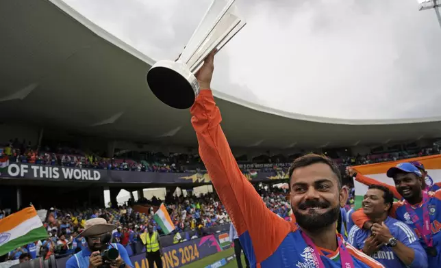 India's Virat Kohli carries the winners' trophy as he celebrates after India won the ICC Men's T20 World Cup final cricket match against South Africa at Kensington Oval in Bridgetown, Barbados, Saturday, June 29, 2024. (AP Photo/Ramon Espinosa)