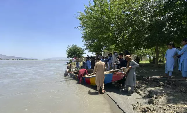 People push the sunken boat from river in Mohmand Dara district of Nangarhar province east of Kabul, Afghanistan, Saturday, June 1, 2024. At least 20 people were killed when a boat sank while crossing a river in eastern Afghanistan Saturday morning, a Taliban official said. (AP Photo)