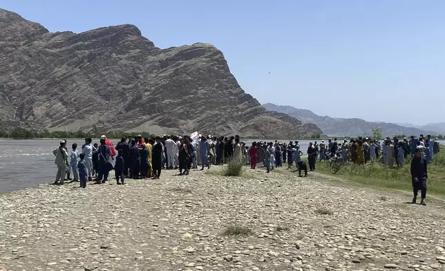 People stand near the site of a sunken boat in Mohmand Dara district of Nangarhar province east of Kabul, Afghanistan, Saturday, June 1, 2024. At least 20 people were killed when a boat sank while crossing a river in eastern Afghanistan Saturday morning, a Taliban official said. (AP Photo)