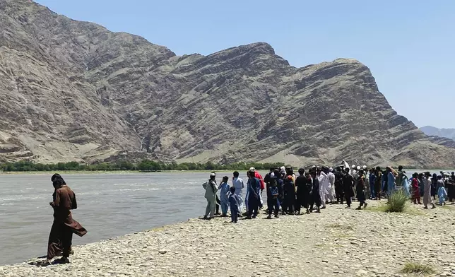 People stand near the site of a sunken boat in Mohmand Dara district of Nangarhar province east of Kabul, Afghanistan, Saturday, June 1, 2024. At least 20 people were killed when a boat sank while crossing a river in eastern Afghanistan Saturday morning, a Taliban official said. (AP Photo)