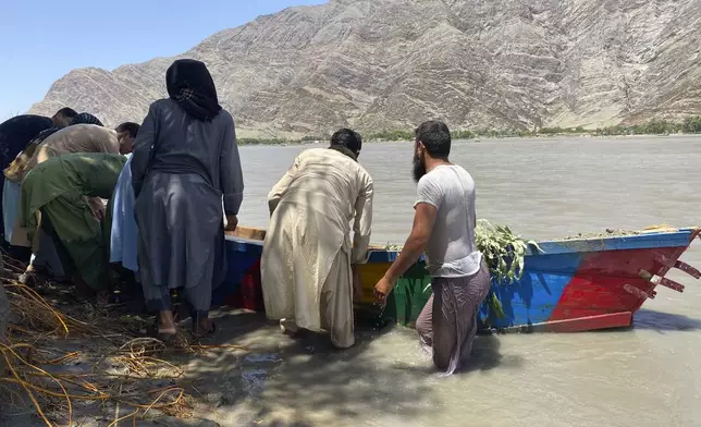 People push the sunken boat from river in Mohmand Dara district of Nangarhar province east of Kabul, Afghanistan, Saturday, June 1, 2024. At least 20 people were killed when a boat sank while crossing a river in eastern Afghanistan Saturday morning, a Taliban official said. (AP Photo)