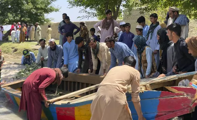 People push the sunken boat from river in Mohmand Dara district of Nangarhar province east of Kabul, Afghanistan, Saturday, June 1, 2024. At least 20 people were killed when a boat sank while crossing a river in eastern Afghanistan Saturday morning, a Taliban official said. (AP Photo)