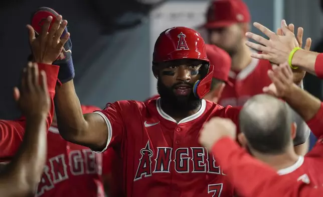 Los Angeles Angels' Jo Adell (7) celebrates in the dugout after scoring off of a single by Taylor Ward during the tenth inning of a baseball game against the Los Angeles Dodgers in Los Angeles, Friday, June 21, 2024. (AP Photo/Ashley Landis)