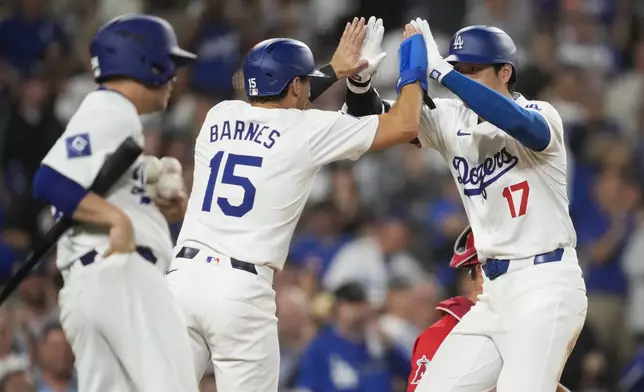 Los Angeles Dodgers designated hitter Shohei Ohtani (17) celebrates with Austin Barnes (15) runs the bases after hitting a home run during the fifth inning of a baseball game against the Los Angeles Angels in Los Angeles, Friday, June 21, 2024. Barnes also scored. (AP Photo/Ashley Landis)