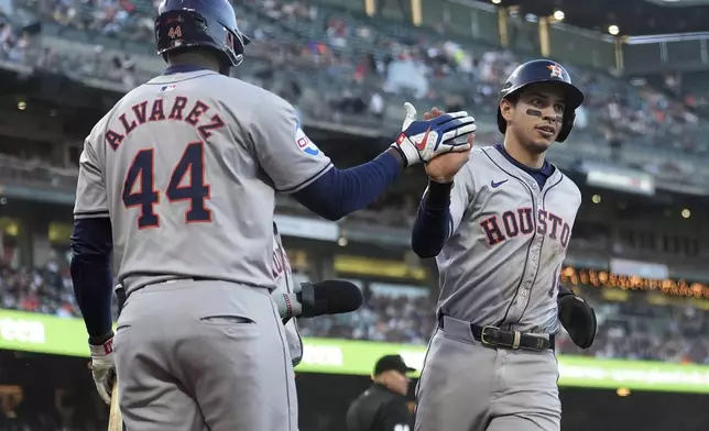 Houston Astros' Mauricio Dubón, right, is congratulated by Yordan Alvarez (44) after scoring against the San Francisco Giants during the fifth inning of a baseball game in San Francisco, Tuesday, June 11, 2024. (AP Photo/Jeff Chiu)