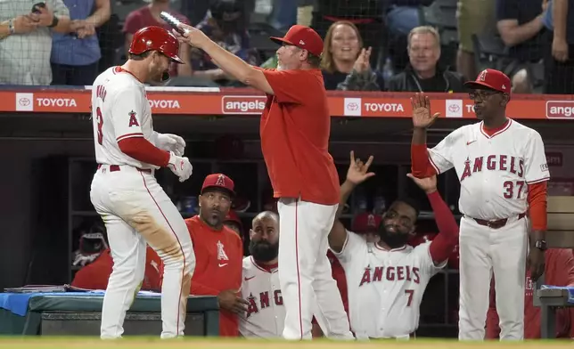 Los Angeles Angels' Taylor Ward, left, is handed an electronic halo after his solo home run against the Oakland Athletics during the seventh inning of a baseball game Tuesday, June 25, 2024, in Anaheim, Calif. (AP Photo/Ryan Sun)