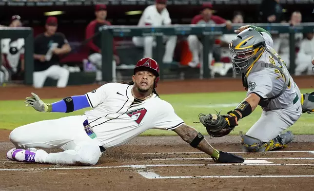 Arizona Diamondbacks' Ketel Marte, left, scores ahead of a tag by Oakland Athletics catcher Shea Langeliers, right, during the first inning of a baseball game Friday, June 28, 2024, in Phoenix. (AP Photo/Ross D. Franklin)