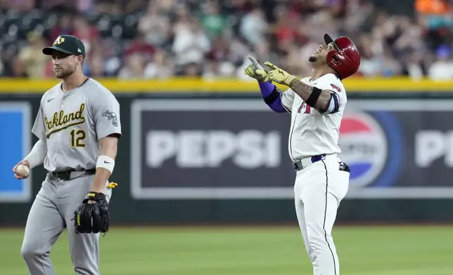 Arizona Diamondbacks' Ketel Marte, right, celebrates his double as Oakland Athletics shortstop Max Schuemann (12) holds the ball during the first inning of a baseball game Friday, June 28, 2024, in Phoenix. (AP Photo/Ross D. Franklin)