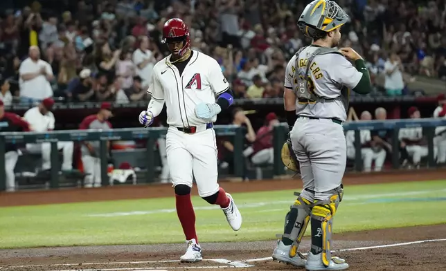 Arizona Diamondbacks' Lourdes Gurriel Jr., left, scores as Oakland Athletics catcher Shea Langeliers, right, looks on for the baseball during the first inning of a baseball game Friday, June 28, 2024, in Phoenix. (AP Photo/Ross D. Franklin)