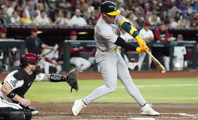Oakland Athletics' Brent Rooker, right, connects for a run-scoring single as Arizona Diamondbacks catcher Tucker Barnhart, left, reaches for the ball during the third inning of a baseball game Friday, June 28, 2024, in Phoenix. (AP Photo/Ross D. Franklin)
