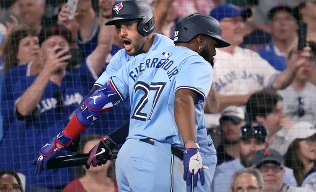 Toronto Blue Jays' Vladimir Guerrero Jr.(27) is congratulated by George Springer after his three-run home run during the seventh inning of a baseball game against the Boston Red Sox at Fenway Park, Monday, June 24, 2024, in Boston. (AP Photo/Charles Krupa)