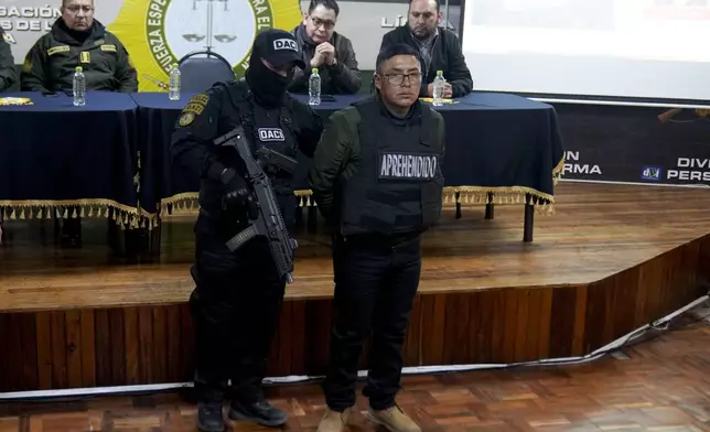 Sergeant Demetrio Mamani is presented to the press in handcuffs by police after his arrest in La Paz, Bolivia, Friday, June 28, 2024. Bolivian government officials said Friday they arrested four more people in connection with Wednesday's failed coup attempt against President Luis Arce, bringing the total detained to 21. (AP Photo/Juan Karita)