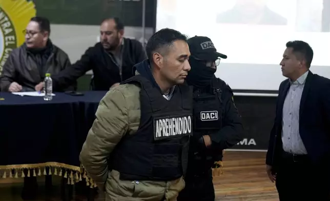 Miguel Angel Burgos is presented to the press in handcuffs by police after his arrest in La Paz, Bolivia, Friday, June 28, 2024. Bolivian government officials said Friday they arrested four more people in connection with Wednesday's failed coup attempt against President Luis Arce, bringing the total detained to 21. (AP Photo/Juan Karita)