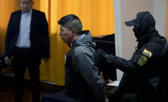 Sergeant Alan Condori is presented to the press in handcuffs by police after his arrest in La Paz, Bolivia, Friday, June 28, 2024. Bolivian government officials said Friday they arrested four more people in connection with Wednesday's failed coup attempt against President Luis Arce, bringing the total detained to 21. (AP Photo/Juan Karita)
