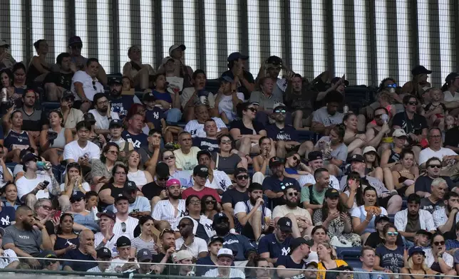 Fans sit in hot weather in Yankee Stadium during the fifth inning of a baseball game between the Atlanta Braves and New York Yankees, Sunday, June 23, 2024, in New York. (AP Photo/Pamela Smith)
